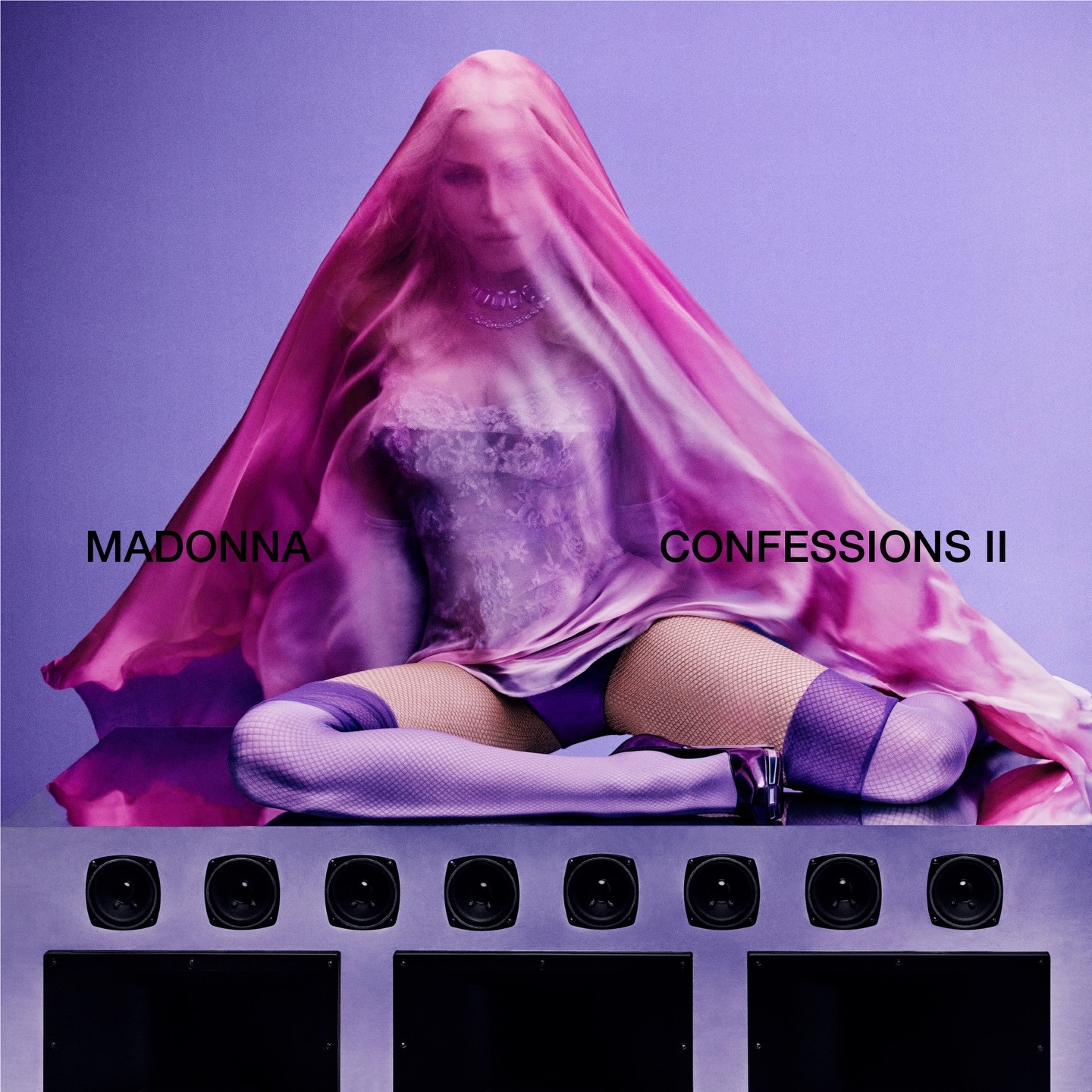 Okładka albumu „Confessions II” Madonny. Artystka siedzi na stosie głośników w fioletowym stroju, z półprzezroczystą różową tkaniną na głowie. Tło jest różowo-fioletowe.
